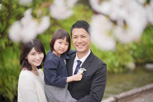 桜の花越しに立つ家族の画像